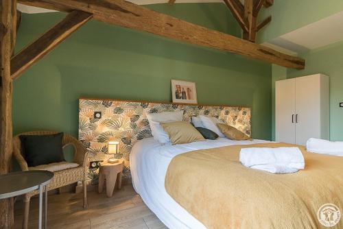 a bedroom with a large bed and a chair at La Ferme des Hautins - Chambres -d'Hôtes in Rieucazé