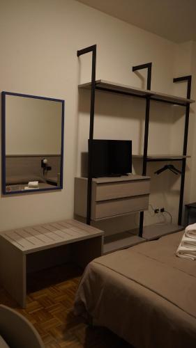 a bedroom with a tv and a mirror and a bed at Hotel Astoria in Fidenza