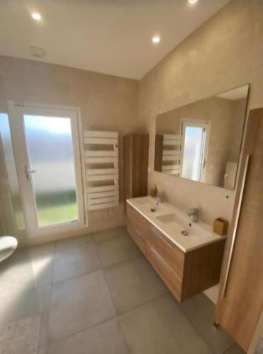 une salle de bain avec un lavabo et un grand miroir dans l'établissement La Perle Mézoise, à Mèze