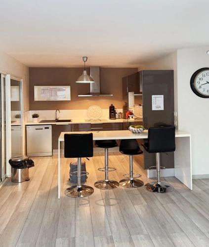 une cuisine avec une table, des chaises et une horloge dans l'établissement Villa Maeva avec piscine, à Latour-Bas-Elne