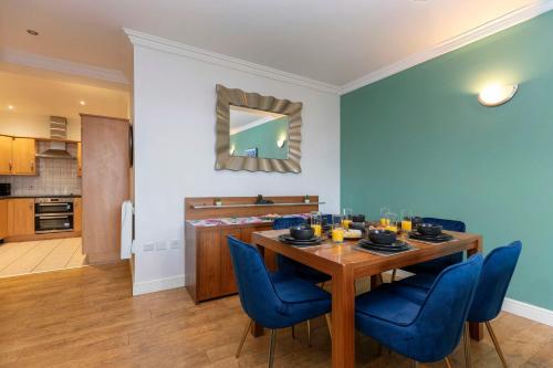 a dining room with a wooden table and blue chairs at Town Centre Spacious Apartment with Private Parking in Middlesbrough