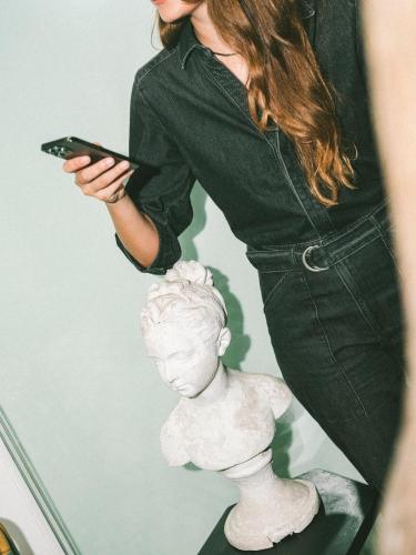 a woman holding a cell phone and a statue at Fausto by Andean in Lima