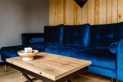 a living room with a blue couch and a wooden table at Lizbona nad Bugiem in Gulczewo