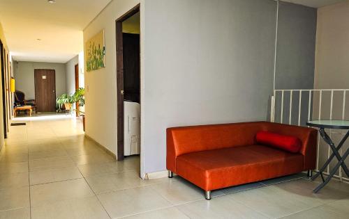 an orange couch in a hallway with a table at Maisant Hostel in Cali