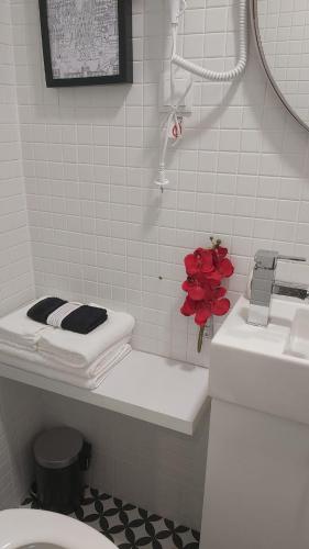 a bathroom with a toilet and a red flower on the counter at Casa 27 - Sete Rios in Lisbon
