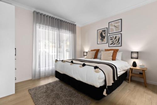 a white bedroom with a large bed and a window at Retreat on Church in Hepburn Springs