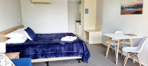 a small bedroom with a bed and a table at Methven Motel & Apartments in Methven