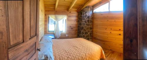a bedroom with a bed in a wooden cabin at Cabaña Paty in Mazamitla