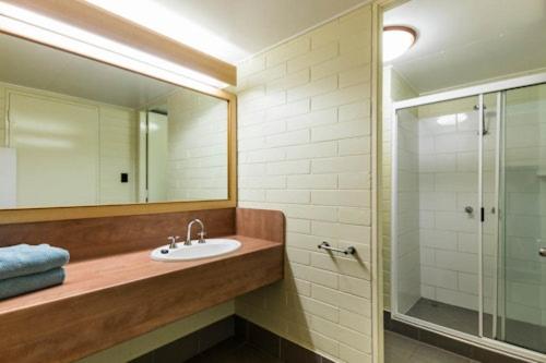 une salle de bain avec un lavabo, une douche et un miroir dans l'établissement Albatross Bay Resort, à Weipa