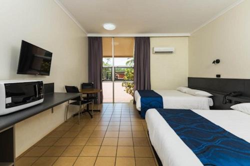 une chambre d'hôtel avec deux lits et une télévision dans l'établissement Albatross Bay Resort, à Weipa
