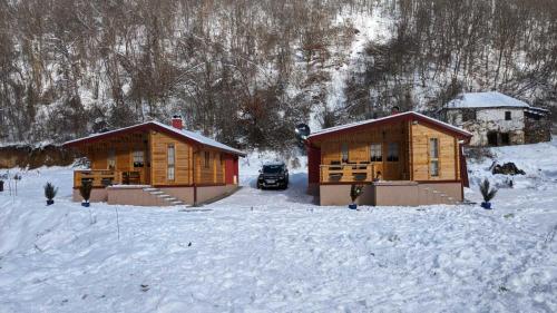 two wooden cabins in the snow with a car at Milica 1 Mezdrejska 87 in Kalna