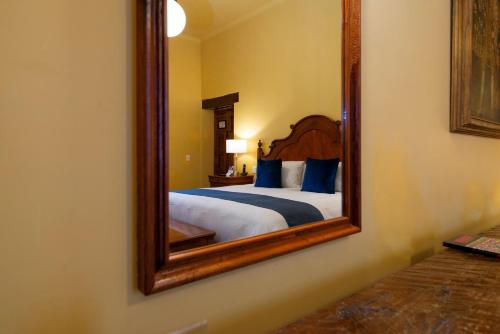 a bedroom with a bed and a mirror on the wall at Hotel Los Juaninos in Morelia