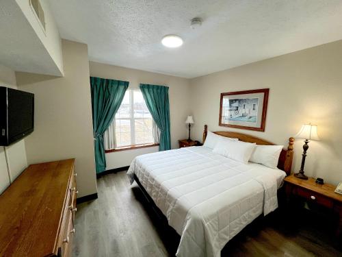 a bedroom with a large white bed and a television at Van Buren Hotel in Shipshewana