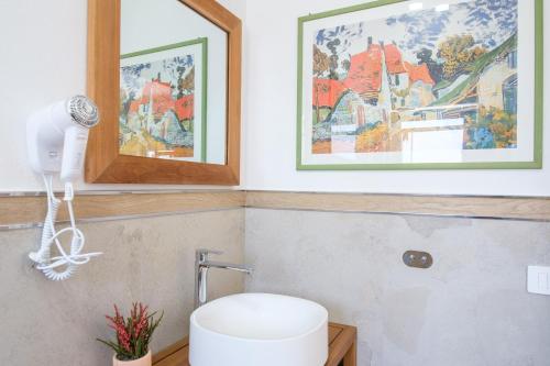 a bathroom with a white toilet and pictures on the wall at Eos affittacamere in Castelsardo