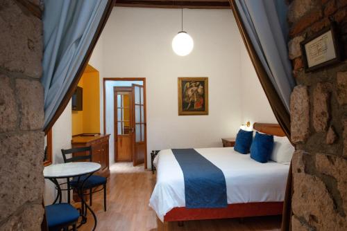 a hotel room with a bed and a table at Hotel Los Juaninos in Morelia