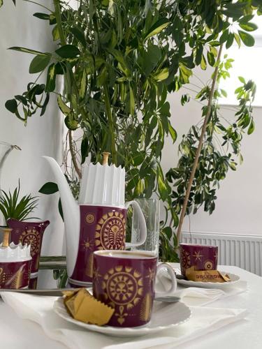 a table with two coffee mugs and a plate of cheese at O5 residence in Nivy