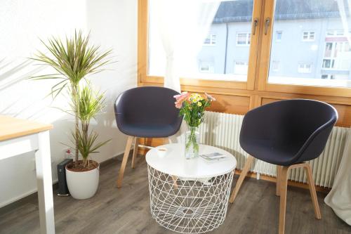two chairs and a table with a vase of flowers at Loft mit Parkplatz und Balkon in Lörrach