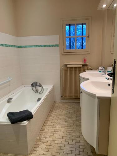 une salle de bain blanche avec une baignoire et un lavabo dans l'établissement Grande maison familiale à la campagne 18kms de Lyon, à Orliénas