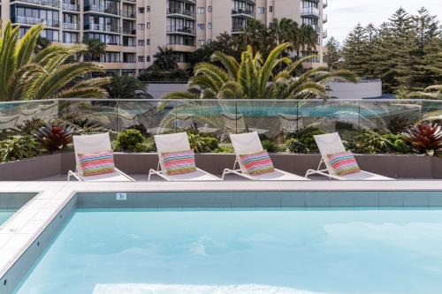 克罗纳拉Rydges Cronulla Beachside的游泳池旁边的一组椅子