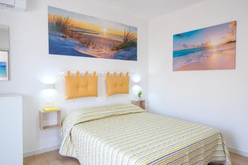a bedroom with a bed and two paintings on the wall at Eos affittacamere in Castelsardo