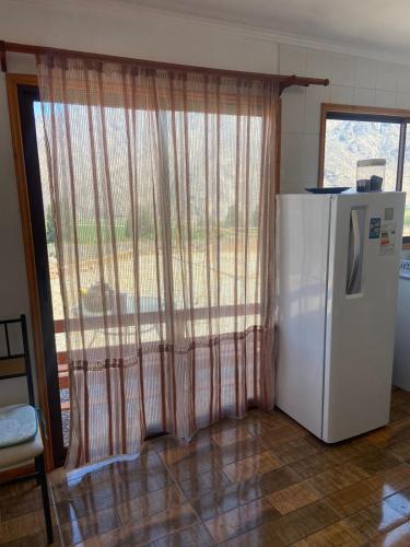 a kitchen with a refrigerator and a large window at Cabañas La Fortaleza in Vicuña