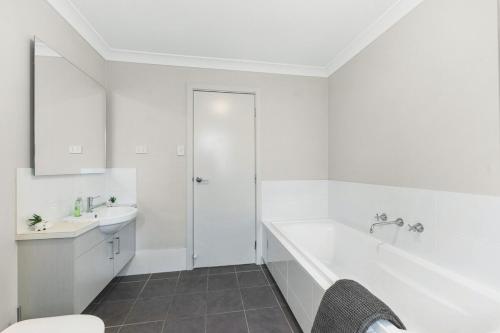 a white bathroom with a tub and a sink at Spacious place to live in the dream of Schofields in Riverstone