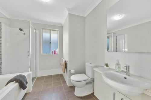 a white bathroom with a toilet and a sink at Spacious place to live in the dream of Schofields in Riverstone
