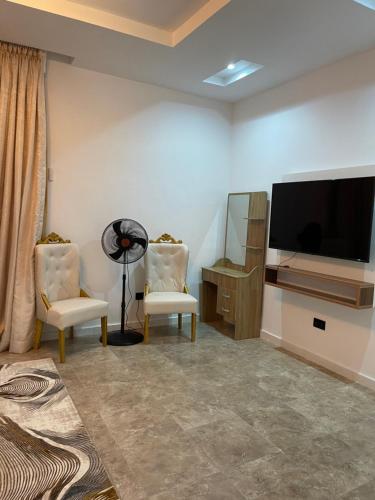 a living room with two chairs and a flat screen tv at Gorgeous 4 Bedrooms Single Family Home at Ibeju, Lekki Lagos in Lekki