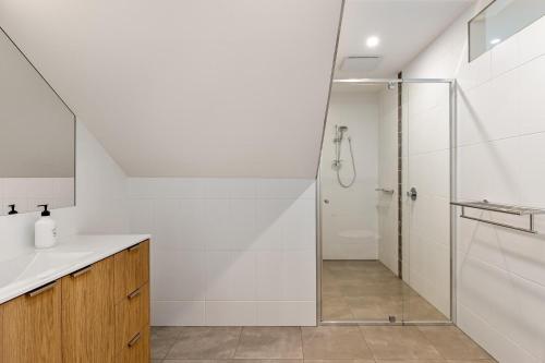 a white bathroom with a shower and a sink at Back Beach in Portsea