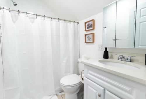 a white bathroom with a toilet and a sink at 4BDR Near Tufts-10min-Walk to Subway-Free Parking in Somerville