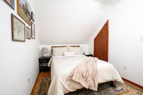 a white bedroom with a bed and a wooden door at 4BDR Near Tufts-10min-Walk to Subway-Free Parking in Somerville
