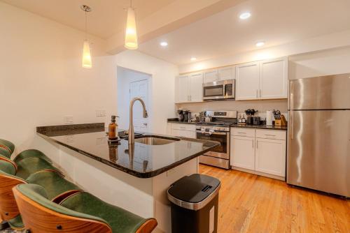 a kitchen with white cabinets and a stainless steel refrigerator at 4BDR Near Tufts-10min-Walk to Subway-Free Parking in Somerville