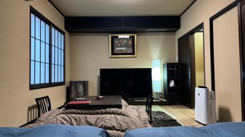 a bedroom with a bed and a table with a television at Oyado Koto No Yume in Takayama