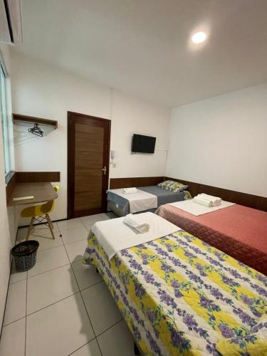 a hotel room with two beds and a desk at Recanto Maria Pureza in Juazeiro do Norte