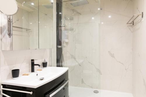 une salle de bain blanche avec un lavabo et une douche dans l'établissement Pelige 3 YourHostHelper, à Cannes