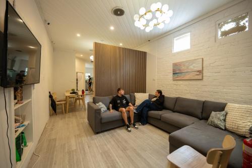 two people sitting on a couch in a living room at Urban Nomad Potts Point - 18 to 39 only in Sydney