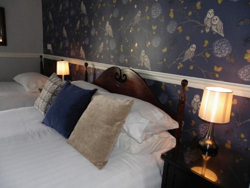 a bedroom with a bed with a blue and yellow wallpaper at Maison Dieu Guest House in Dover