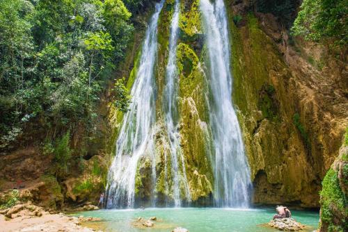 a waterfall with two people in a pool in front of it at Oceanfront Apt W- Private Beach - Las Terrenas in El Limón
