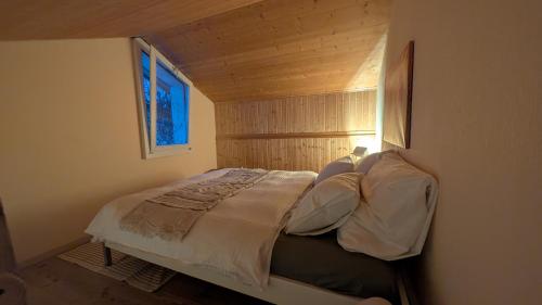 a bed in a small room with a window at Casa14 - Swiss houses in Steffisburg
