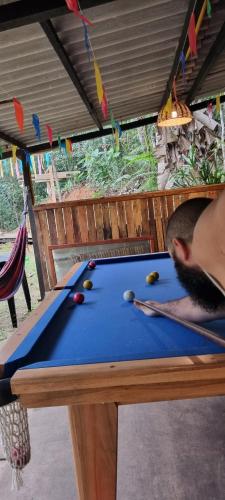 un hombre jugando al billar en una mesa de billar en Eco Camping do Véu, en Majé