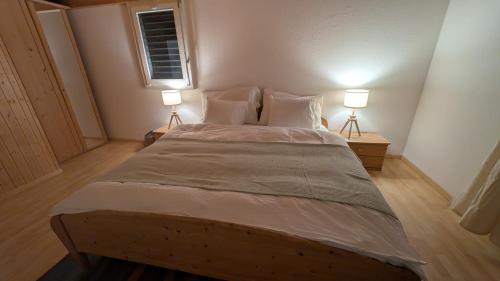 a bedroom with a large bed with two lamps at Casa14 - Swiss houses in Steffisburg