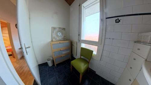 a small bathroom with a green chair and a window at Casa14 - Swiss houses in Steffisburg