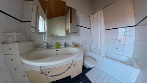 a bathroom with a sink and a tub and a toilet at Casa14 - Swiss houses in Steffisburg