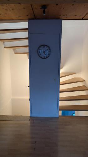 a blue door with a clock on it next to stairs at Casa14 - Swiss houses in Steffisburg