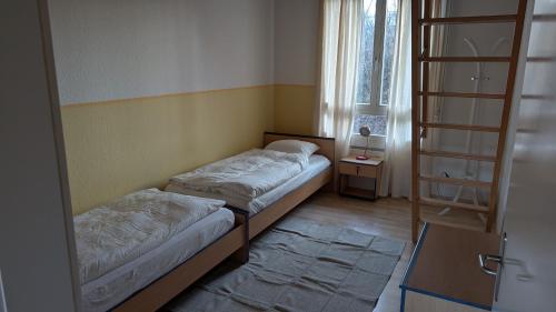 two beds in a small room with a window at Casa14 - Swiss houses in Steffisburg