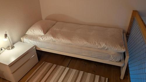 a small bedroom with a bed and a night stand at Casa14 - Swiss houses in Steffisburg