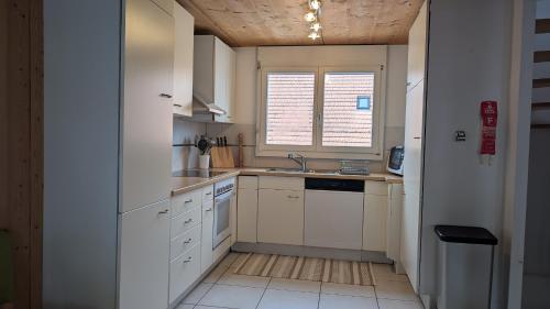 a kitchen with white cabinets and a sink and a window at Casa14 - Swiss houses in Steffisburg