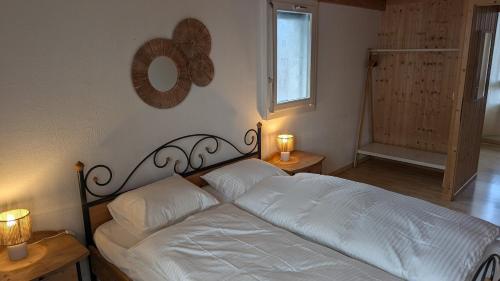 a bedroom with a bed with white sheets and two lamps at Casa14 - Swiss houses in Steffisburg