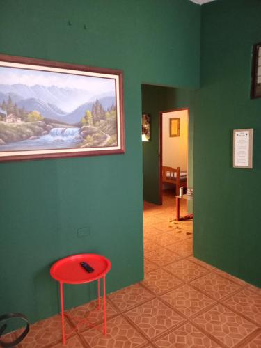 a room with a red stool and a painting on the wall at Hospedaje Beliz Cambalache in Liberia