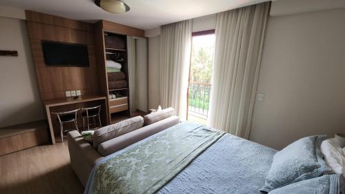 a bedroom with a bed and a couch and a television at Pedra Azul - Flat Particular in Pedra Azul